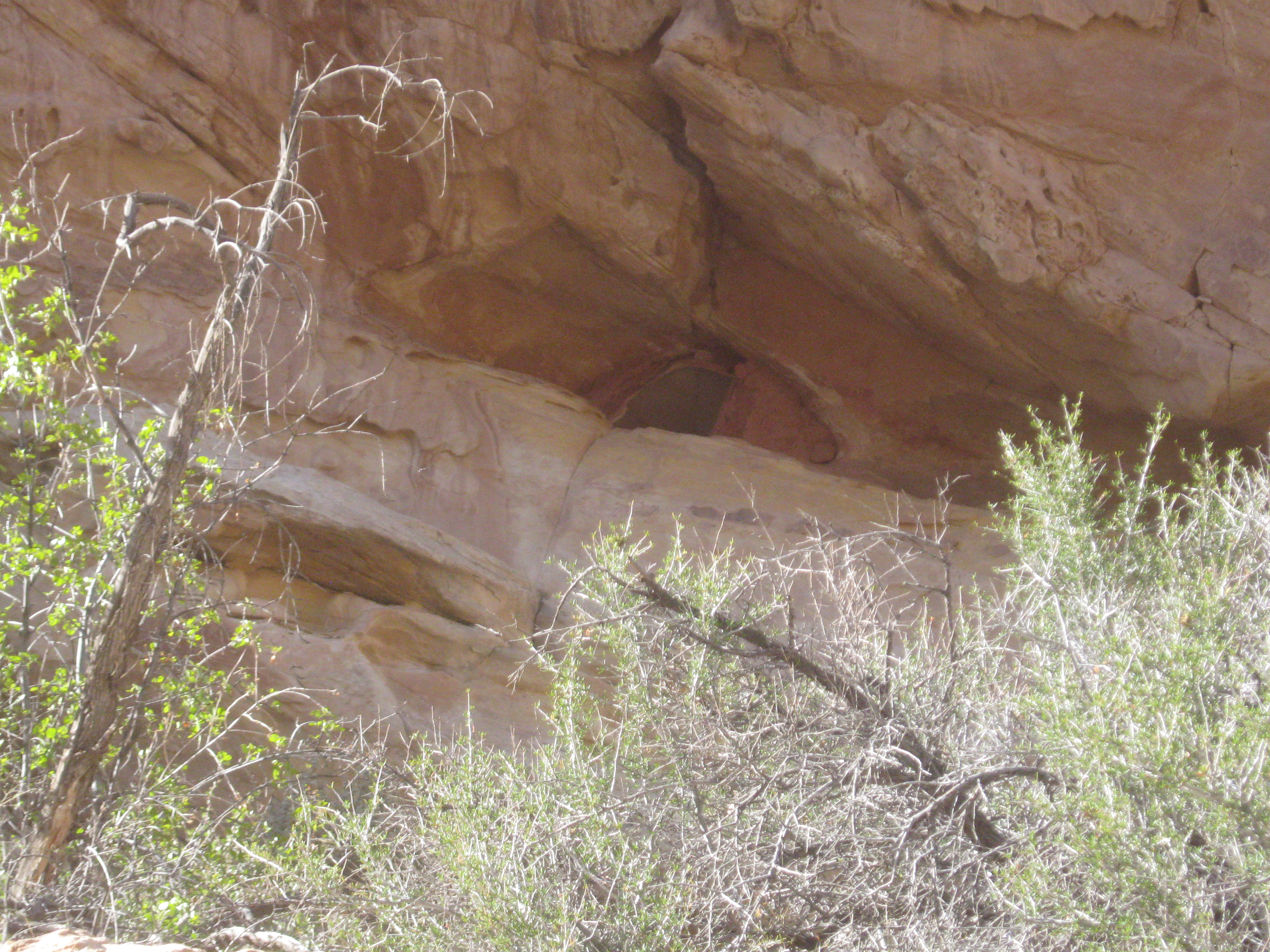 A small Fremont stone granary built into a sandstone cliff alcove high above the valley floor in Wayne County, Utah
