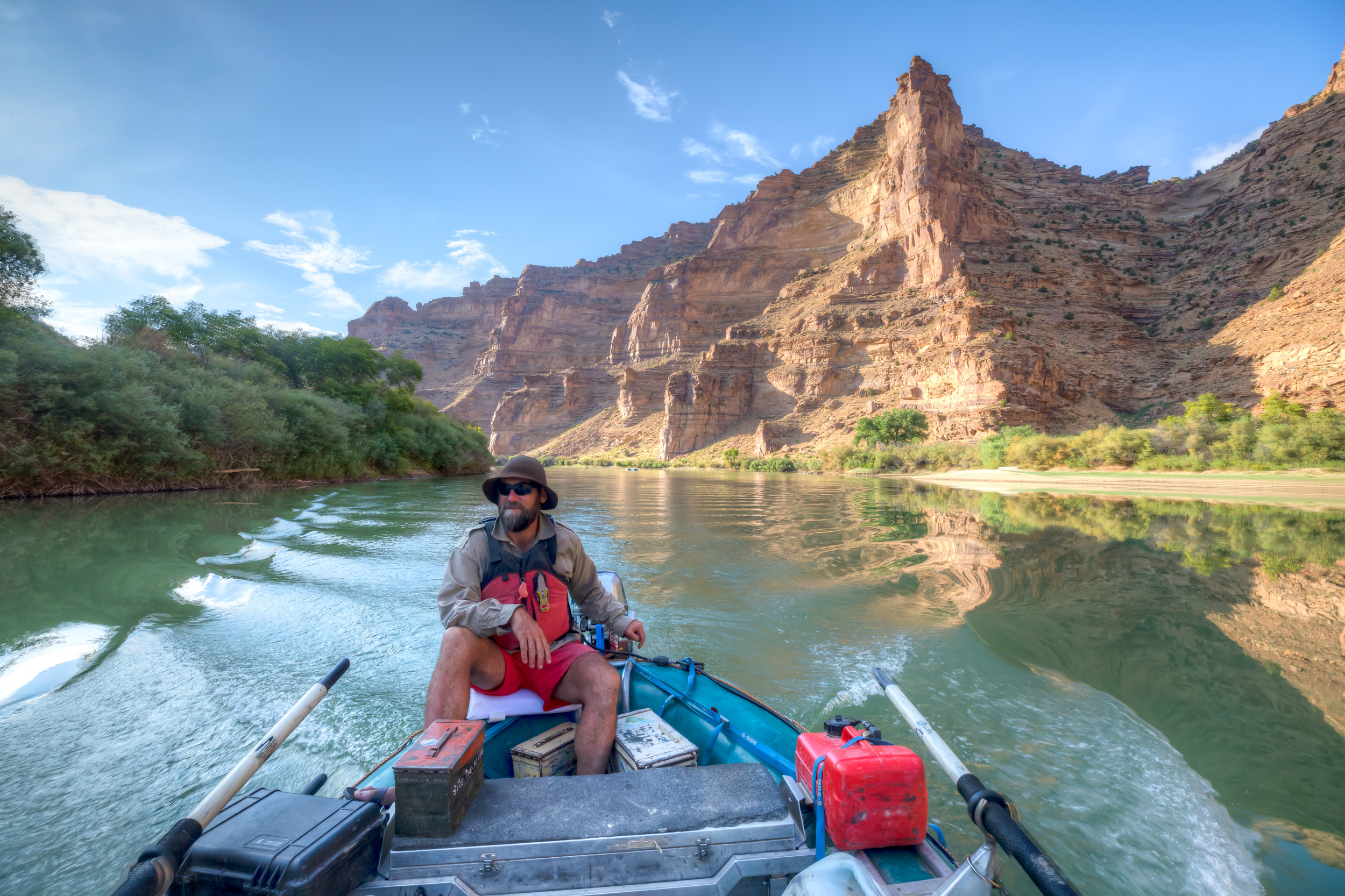 A lone rafter paddling the Green River through the towering sandstone walls of Desolation Canyon, Utah